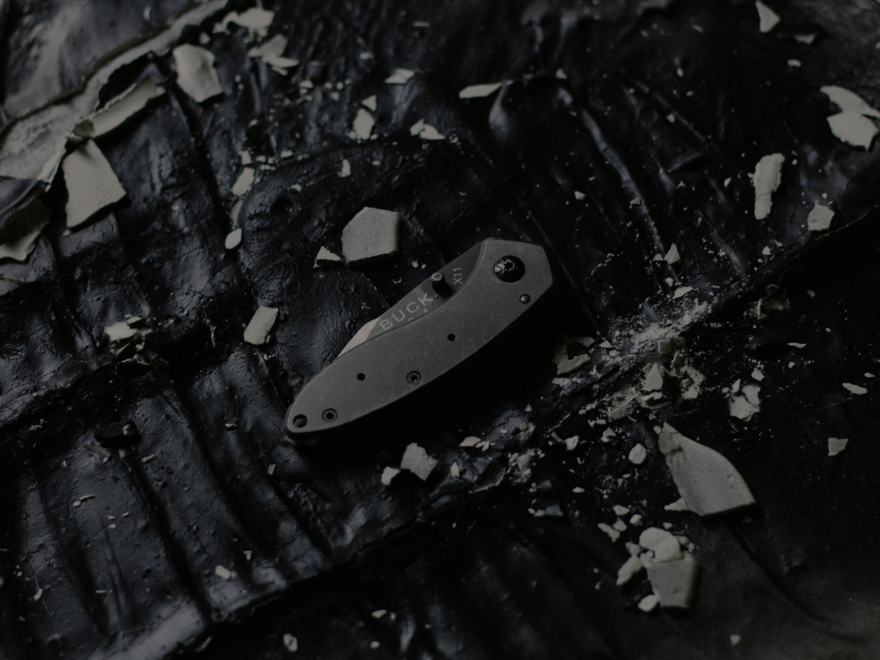 A folding knife resting on charred wood
