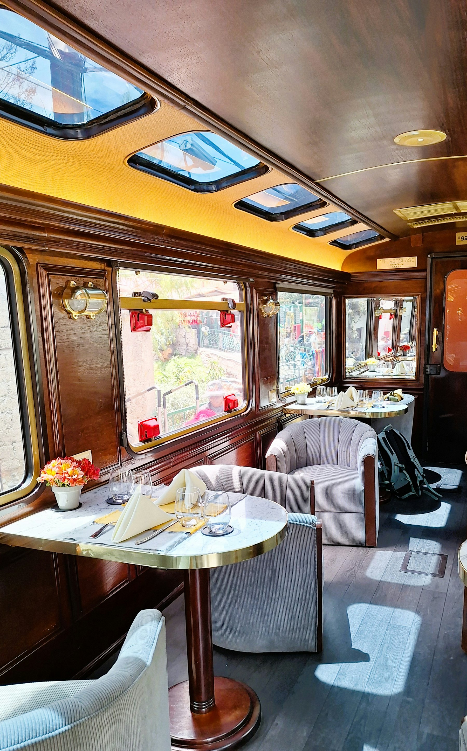 A wood-panelled dining carriage with set tables and warm lamps